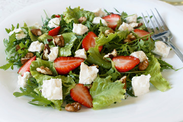 Light spring salad on a white background. Proper nutrition. Diet. Proper nutrition. Diet. Slat with greens, strawberries and cheese