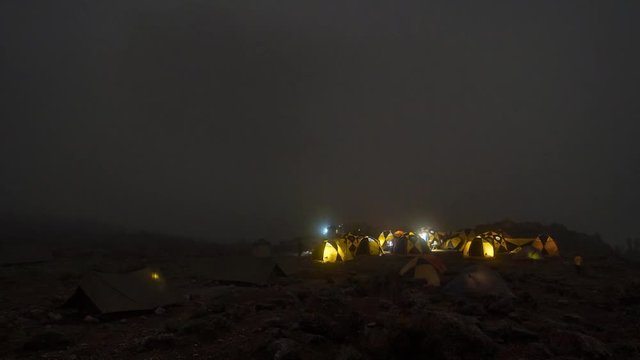 Pitched tents camping at the base of Mount Kilimanjaro. Beautiful timelapse view of the clouds moving over the tents.