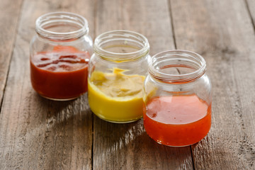 Small jars of various sauces on wooden table