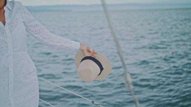 Girl holding a hat over the sea