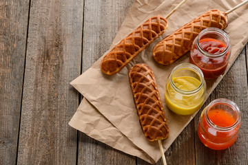 Corn dogs and jars of mustard, ketchup and barbecue sauce