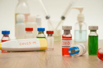 coronavirus outbreak, Virus and recovery concept, there are a lot of vaccine bottles with red or green liquid, syringe, alcohol and digital fever thermometer on wooden table