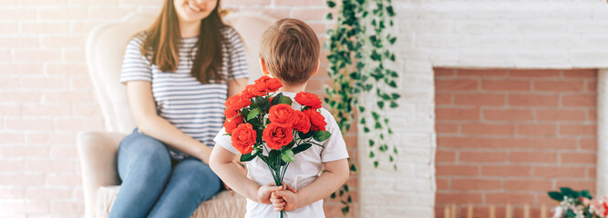 Boy holding a bouquet of flowers behind his back, the son gives his mother flowers, what to present...