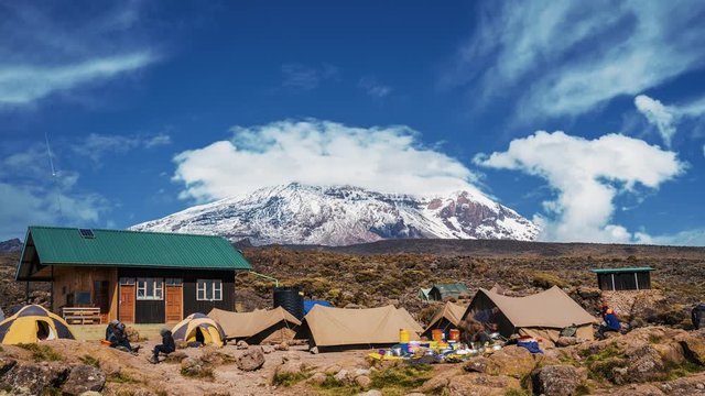 Pitched tents camping at the base of Mount Kilimanjaro. Beautiful timelapse view of the clouds moving over the tents.