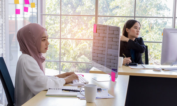 Muslim women and girls of different nationalities sit and work in a modern office. Professional and happy working concept