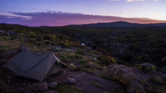 Pitched tents camping at the base of Mount Kilimanjaro. Beautiful timelapse view of the clouds moving over the tents.