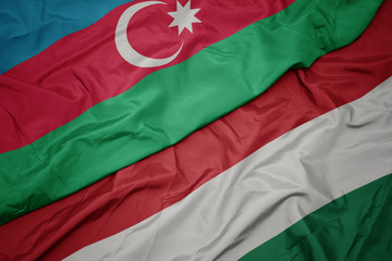 waving colorful flag of hungary and national flag of azerbaijan.