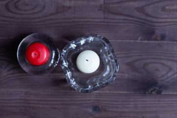 White and red candles in glass holders on wooden background