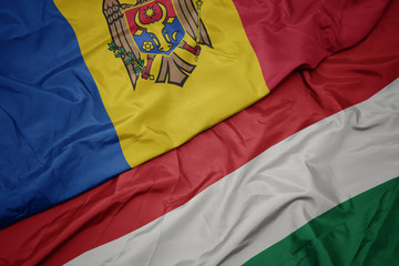 waving colorful flag of hungary and national flag of moldova.