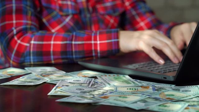 Cinemagraph dollar bills falling on table of freelancer working online