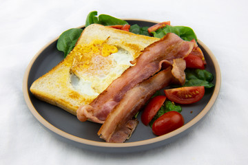 Egg in a hole bread and bacon with salad