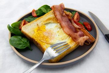 Egg in a hole bread and bacon with salad