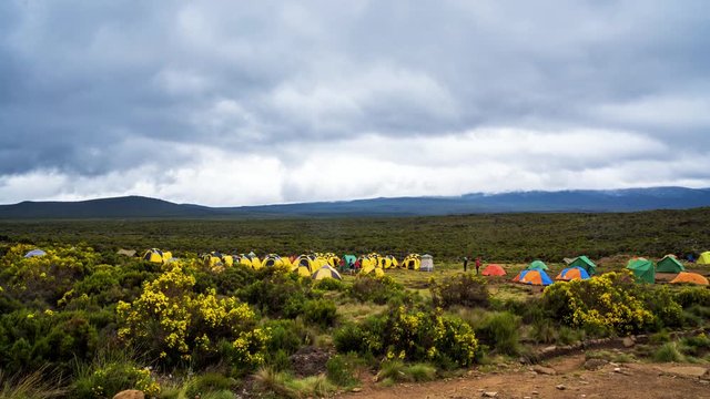Pitched tents camping at the base of Mount Kilimanjaro. Beautiful timelapse view of the clouds moving over the tents.