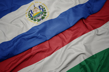 waving colorful flag of hungary and national flag of el salvador.