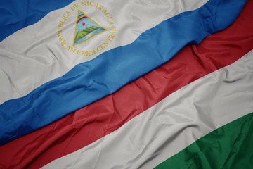 waving colorful flag of hungary and national flag of nicaragua.