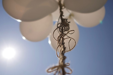 BIAŁE BALONY NA SPLĄTANYM SZNURKU NA TLE NIEBIESKIEGO NIEBA © Grzegorz