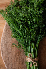 A bunch of dill tied with twine on a wooden background