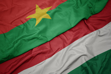 waving colorful flag of hungary and national flag of burkina faso.