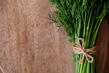 A bunch of dill tied with twine on a wooden background