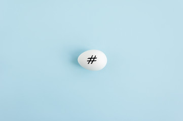 Hashtag sign on a white natural egg. Minimal Easter concept. Copy space for text.
