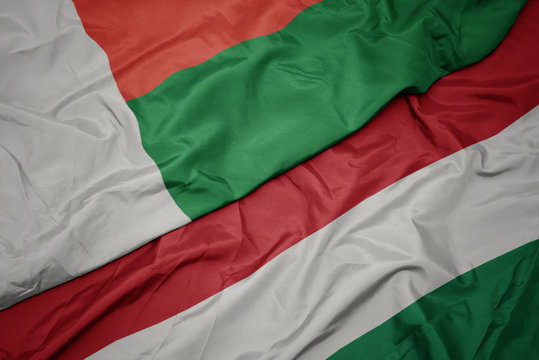 waving colorful flag of hungary and national flag of madagascar.