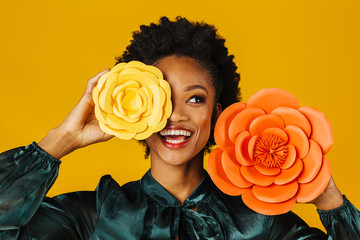 Portrait of a happy smiling young woman with orange and yellow flower blooms covering one eye and looking up