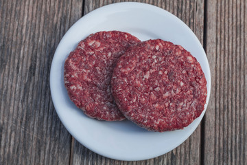 raw burger minced red meat on wooden background on plate