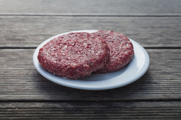 raw burger minced red meat on wooden background on plate