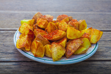 Tapa de patatas bravas o patatas gajo humeantes recién hechas en un plato blanco sobre mesa de...
