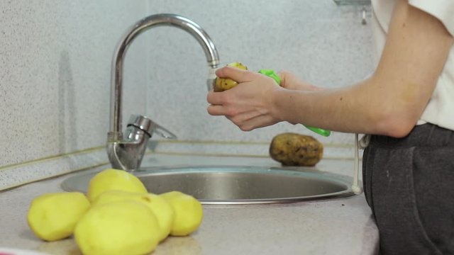 Hands clean peel potato in sink