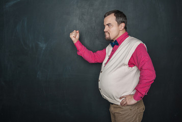 Angry teacher threatens with fist on blackboard background
