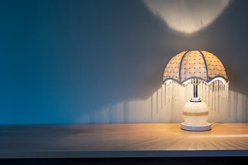 A luminous lamp in the shadow, a table lamp on the desk 