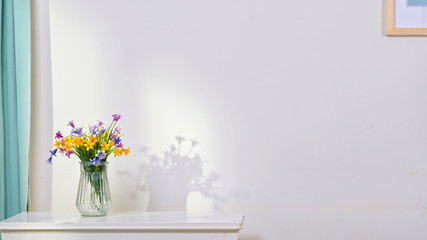 Bouquet of colorful flowers in a vase on white table in interior room. Empty space for text. White...