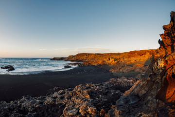 Coastline with lava cliffs and ocean at sunset in Lanzarote, Canary Islands.
