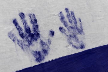 Blue painted hand print on white wall. Human hand, palm, fingers.