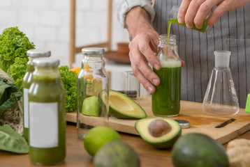 Man vegetarian adding green extract to detox smoothie