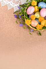 Easter. Congratulations on the spring holiday of Easter. Colorful eggs in a basket decorated with flowers and grass.
