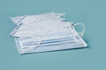 four new disposable medical masks lie on blue surface, pandemic, selective focus
