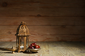 Muslim lamps and dates on wooden background