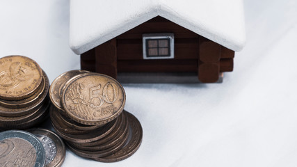 scandinavian house model put behind the pile of euro coins, mortage loan or  real estate investment concept