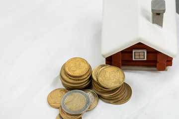 scandinavian house model put behind the pile of euro coins, mortage loan or  real estate investment concept