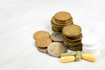 concept of healthcare system recovery for COVID-19 crisis in EU, euro coins stacked and pills on clean and nice white textile fabric.