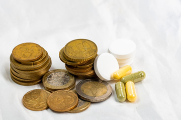 concept of healthcare system recovery for COVID-19 crisis in EU, euro coins stacked and pills on clean and nice white textile fabric.