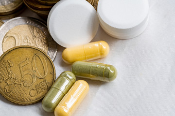 concept of healthcare system recovery for COVID-19 crisis in EU, euro coins stacked and pills on clean and nice white textile fabric.