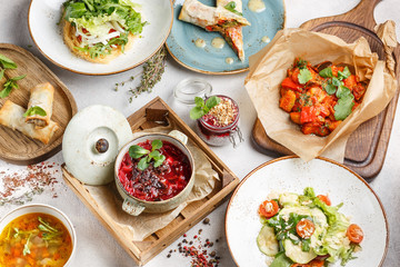 Vegetarian dishes on a white table, soups, vegetable salads, stewed vegetables. Healthy lean food. Menu for cafes and restaurants.