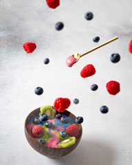 Smoothie bowl levitation. Flying berries over the smoothie with spirulina and banana. Detox, healthy nutrition, dieting, superfoods