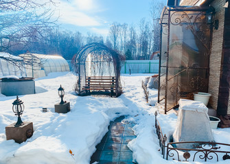 Countryside dug up the ground with the remnants of melted snow in the village in early winter, spring, a puddle, a well, a gazebo, pavers, sunny day outdoor. Russia