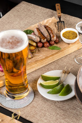 weisswurst grilled sausages served with baked potato and mustard for Octoberfest with glass of beer at restaurant