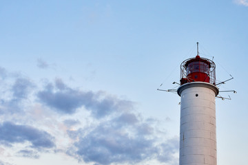Red and white lighthouse at sunset against blu sky background, copy space. Summer seascape with light house