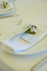 Table set with blank guest card, plate with white napkin and cutlery on table, copy space. Place setting at wedding reception. Table served for wedding banquet in restaurant